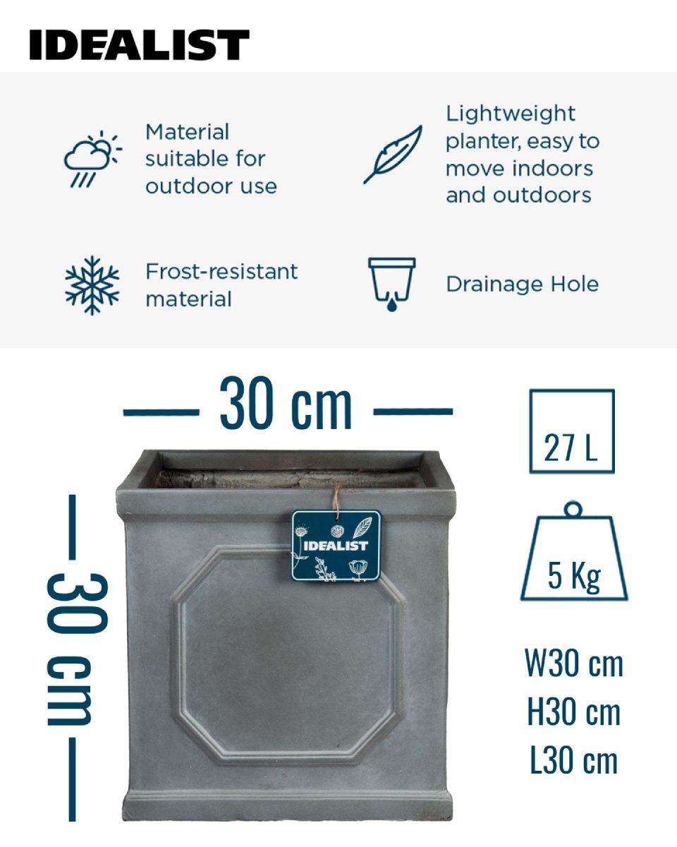 An IDEALIST Lite Chelsea Flower Box Square Garden Planter (W30 H30 L30 cm, 27L, Faux Lead Light Stone) sits on a patio with wicker chairs and table, brick wall, black fence, green grass, and an umbrella shading this cozy outdoor retreat.