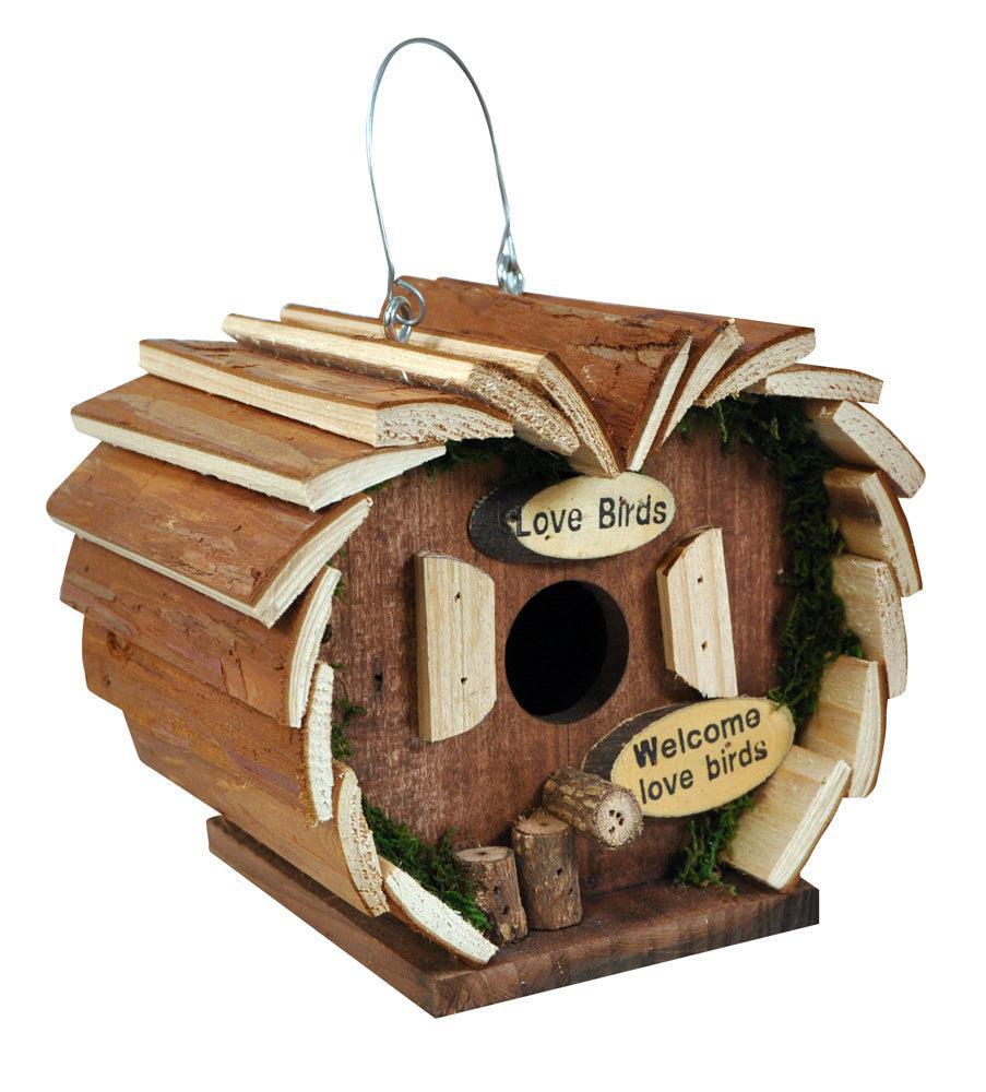 The Wooden Crafted Bird Hotel is a charming log cabin-shaped nesting box with a circular entry hole, two front signs—&quot;Love Birds&quot; and &quot;Welcome love birds&quot;—and a sturdy metal hanging wire for easy display.