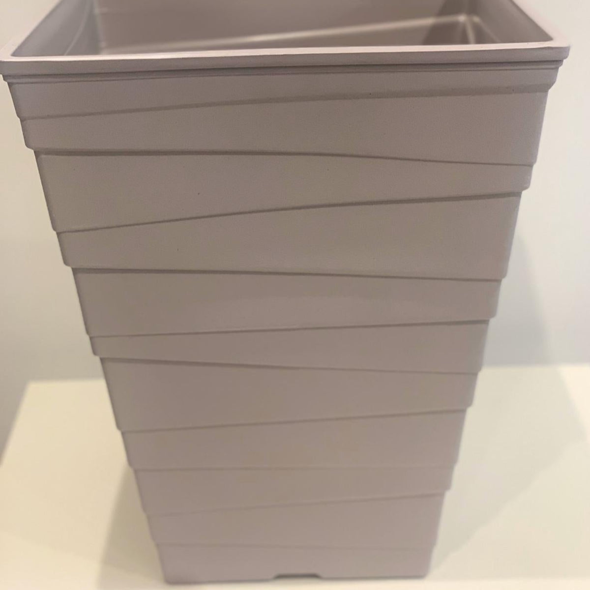The Luxury Ripple Plastic Plant Pot - GREY is a tall, light gray rectangular pot with horizontal wavy lines, displayed on a white surface against a plain background.